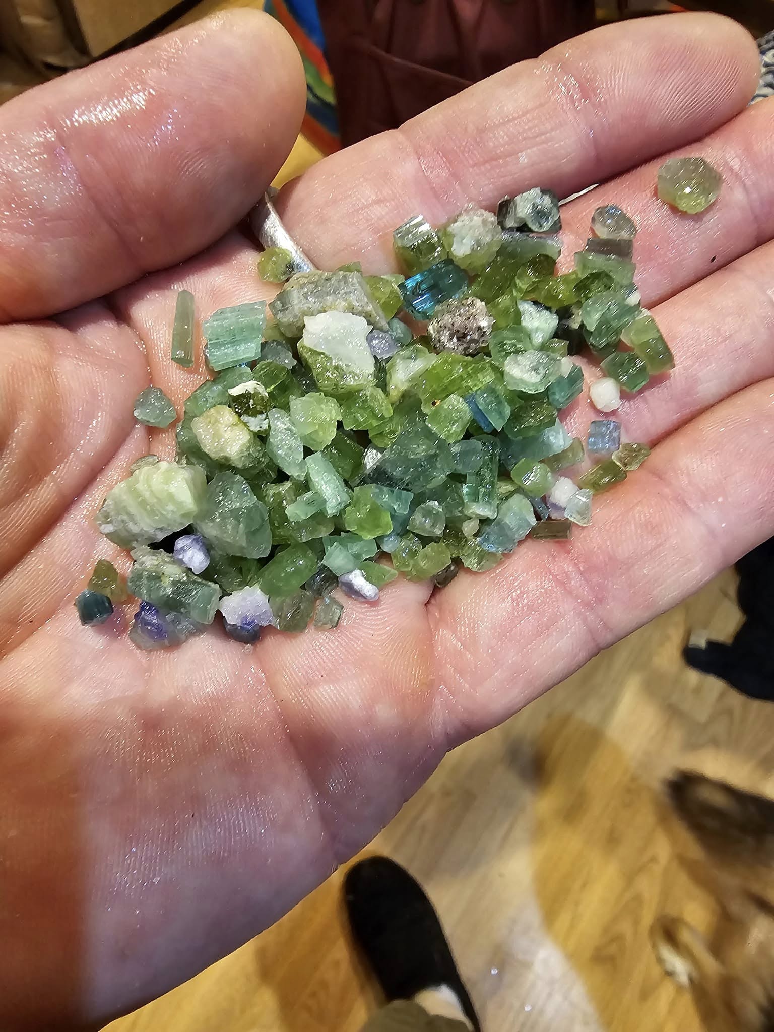 Raw green tourmaline crystals from Maine mines, held in hand